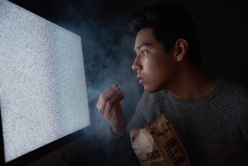 homem comendo pipoca assistindo tv