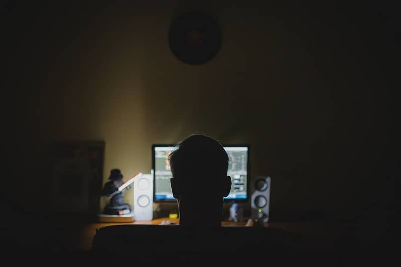 homem olha para a luz do monitor em uma sala escura