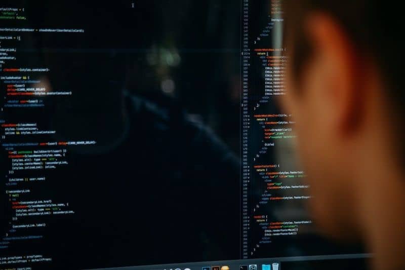 homem na frente de uma tela preta com muitos códigos