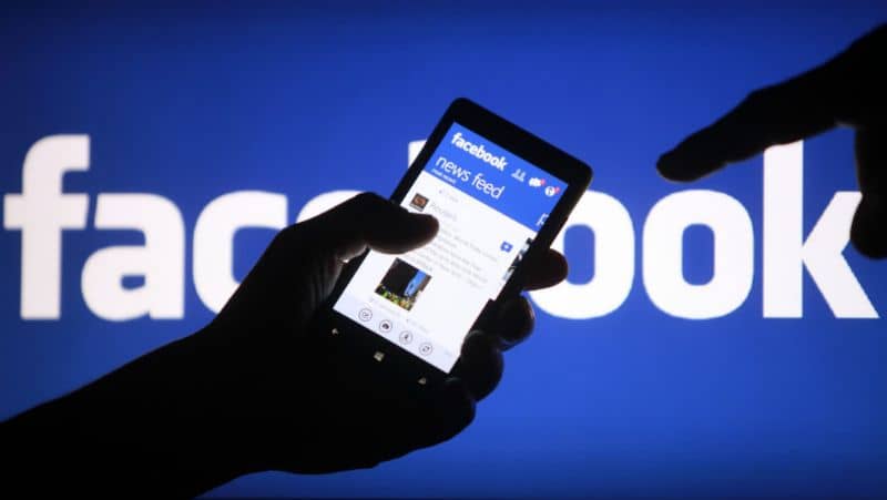 Facebook, homem com celular na mão