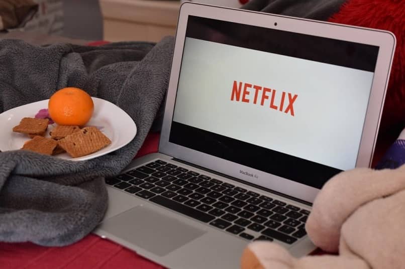 laptop no netflix com um prato de comida ao lado